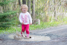 toddler girl splashing in a puddle 