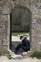 woman in grief sitting on the floor in an archway