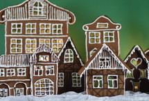 home made gingerbread village in front of green background on white snowlike velvet as advent decoration