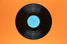 old black vinyl record with blank cyan label central on orange background