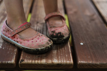 a little girl with muddy shoes 