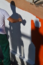 man painting over a red wall 