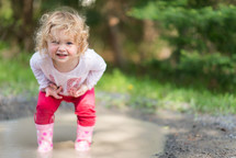 toddler girl playing in a puddle 