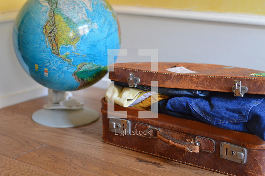 a globe and a packed suitcase 
