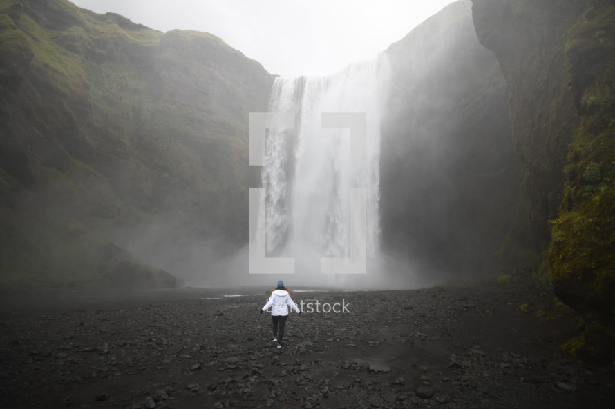 a person walking towards a waterfall 