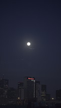 full moon in the night sky over a city 