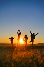 Silhouette of jumping kids against summer sunset 