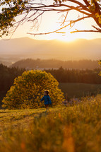 Boy walking on a field during sunset