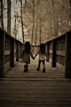 sisters walking on a boardwalk holding hands 