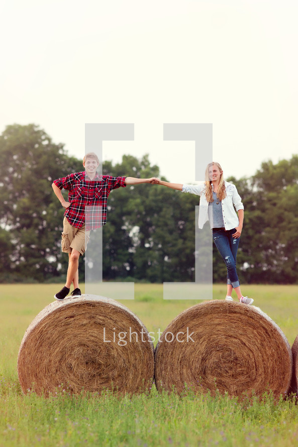 man and woman standing on hay bales 