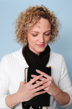 Woman praying holding a Bible 