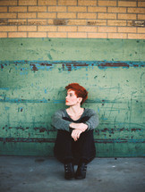redhead sitting on a sidewalk