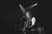man with dread playing a guitar on stage 