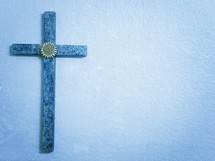 Blue textured cross on a blue background with copy space