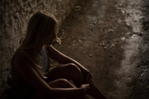 a woman sitting in a dark hallway 