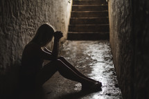 a woman sitting alone in a dark hallway