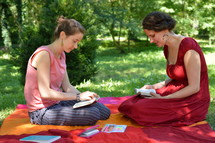 women reading Bibles on a blanket in the grass 