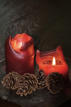 melting wax and flames on red candles and pine cones 