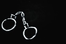 A chalk drawing of a pair of handcuffs.