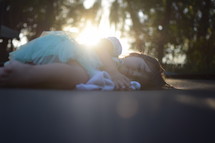 a toddler girl sleeping on a trampoline under rays of sunlight 