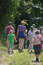 families walking on a path outdoors through a forest