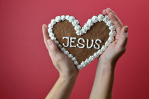 hands holding up a cookie with the word Jesus 