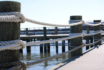 Ropes and posts on a pier in the water.