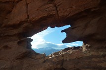 view of mountains through an opening in red rock 