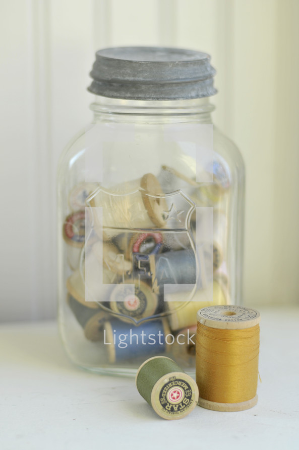 Spools of thread in a jar.