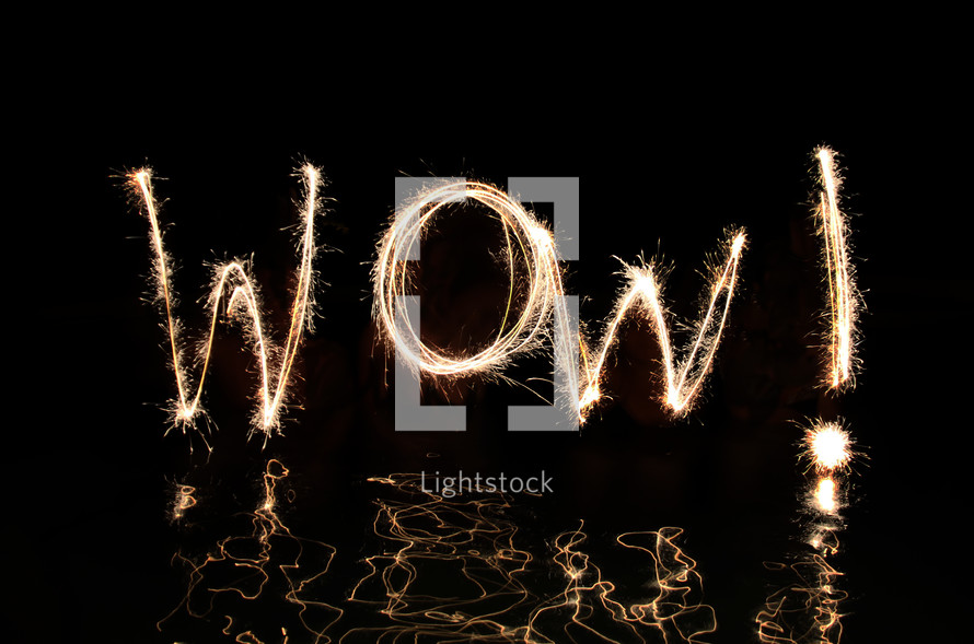 "Wow" written in fireworks by  four 'artists' standing up the their waists in water.