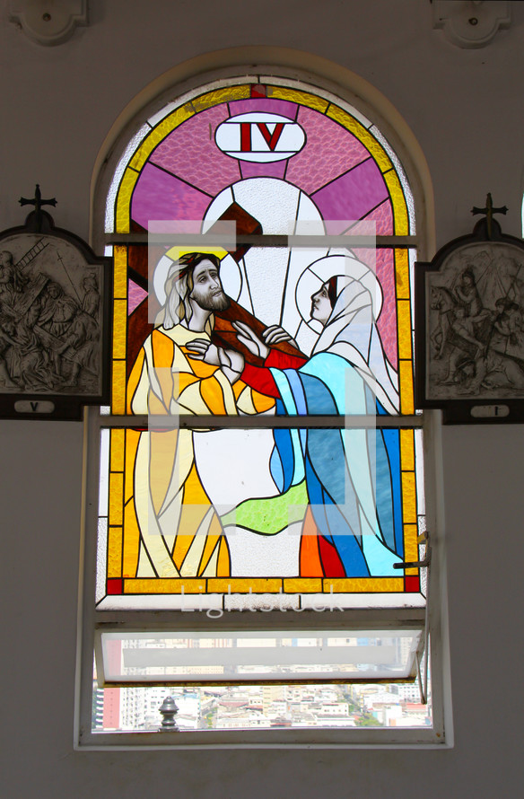 A stained glass window depicting Mary and Jesus carrying the cross.