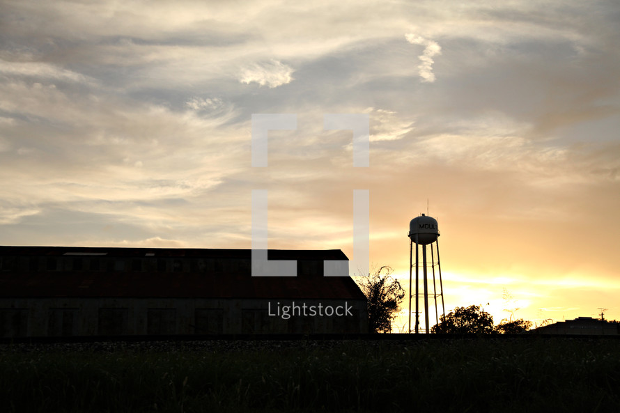 A barn and a water tower at sunset.