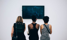 women in an art gallery looking at a photograph