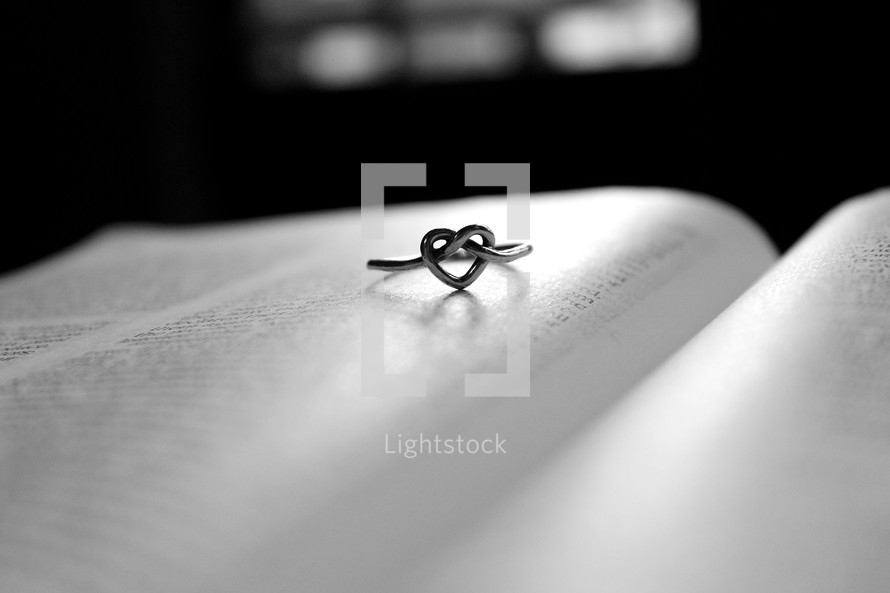 Heart knot ring on page of open Bible.