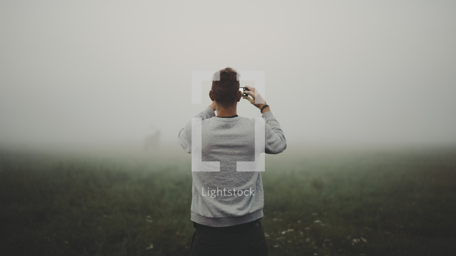 a man with a cellphone taking a picture of fog 