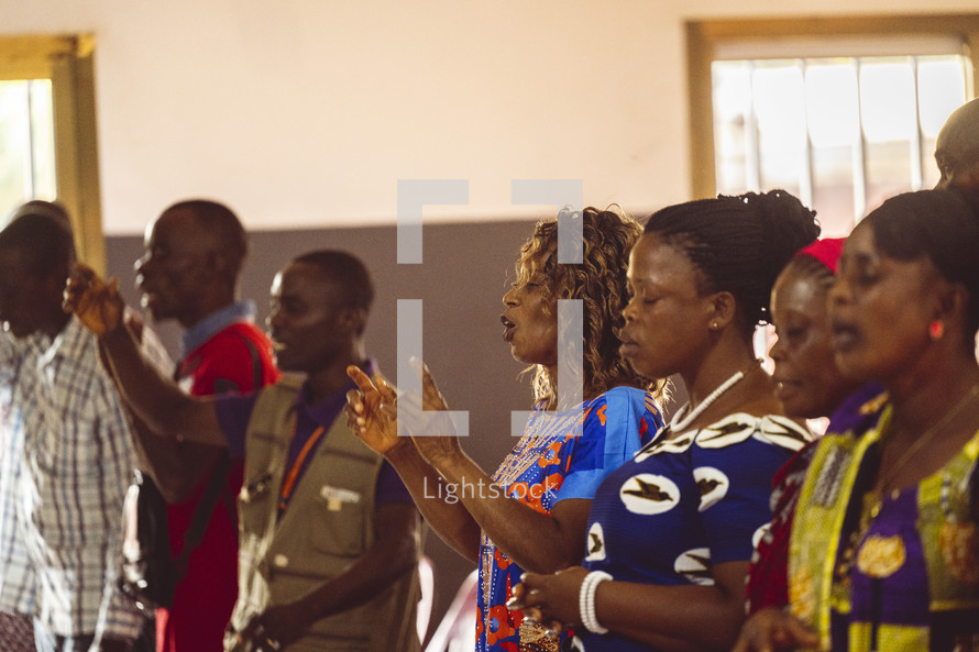 African people singing, praising God, worshiping and lifting their hands in a small village of the ivory coast in west Africa.