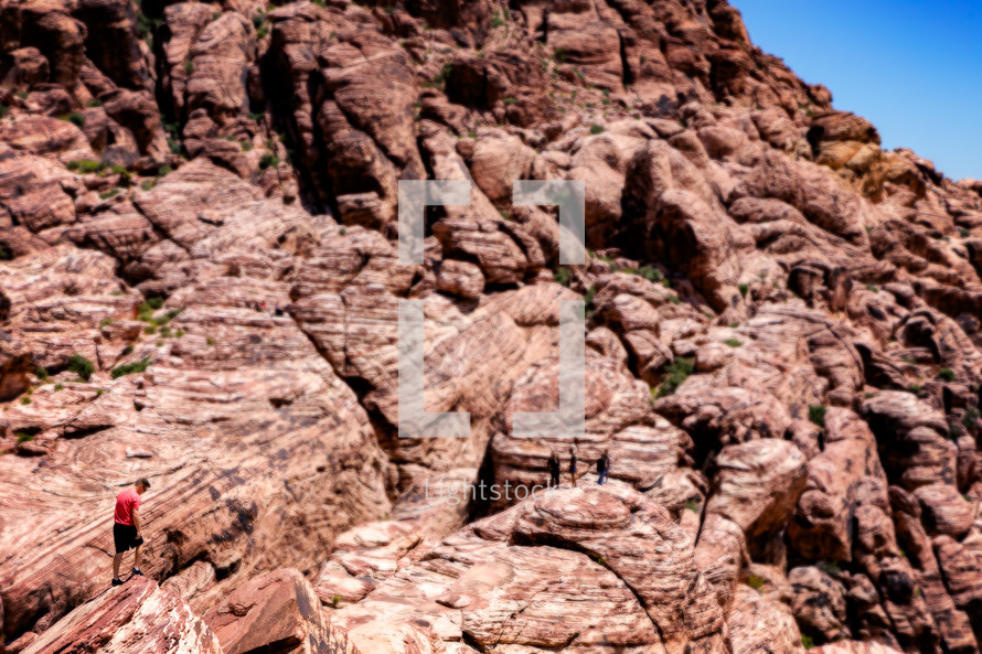 a man exploring red rock cliffs 
