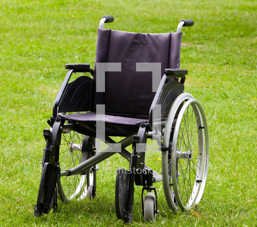 Empty wheelchair on grass field in the park