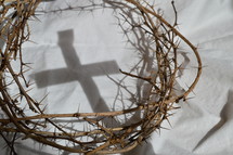 crown of thorns on white cloth and cross shadow 