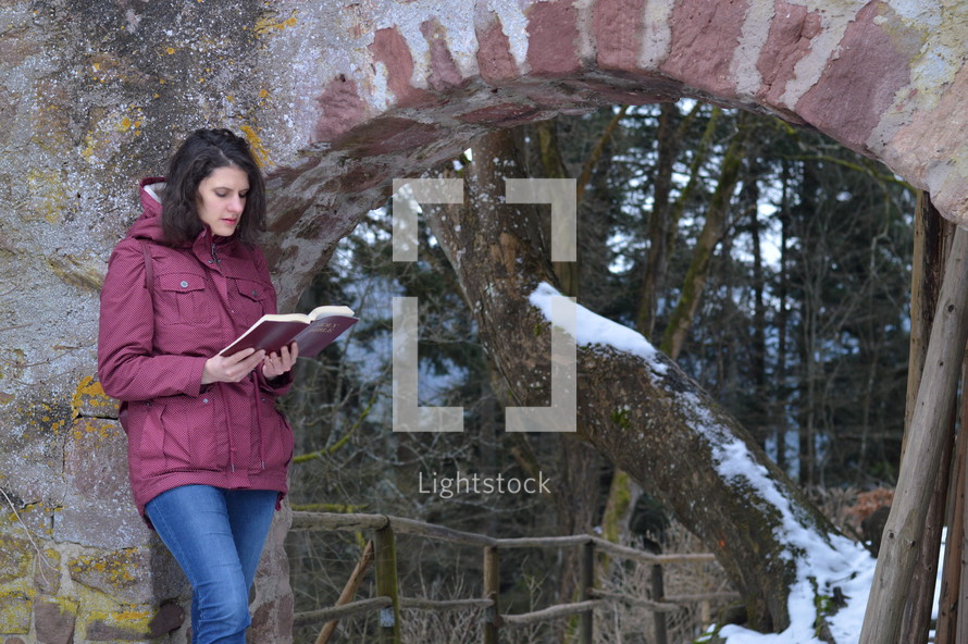 a woman reading a Bible outdoors in winter 