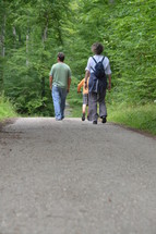 a family walking on a trail through the woods 