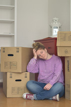 a woman sitting on the floor next to moving boxes 