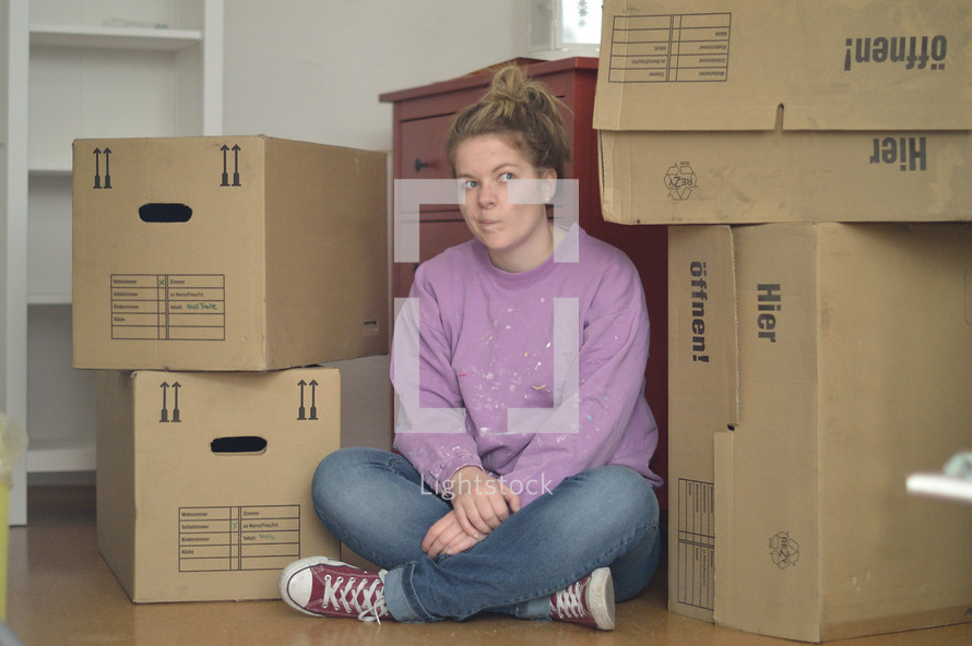 a woman sitting next to moving boxes 