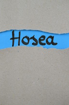 Hosea - torn open kraft paper over blue paper with the name of the prophetic book  Hosea