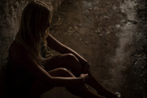 a woman sitting alone in a dark hallway 