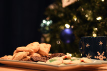 plate of Christmas cookies in front of a Christmas tree 