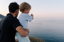 Son showing father a boat on the sea