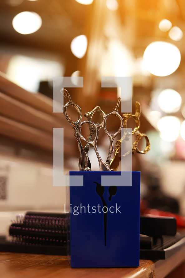 Professional hairdressing tools. Various steel scissors and combs, hairbrushes on wooden table on barbers workplace at barbershop salon. The concept of the hairdressing beauty industry. Copy space.