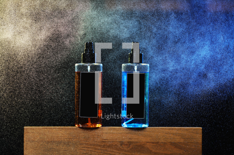 two bottles with yellow and blue liquid. two spray spraying cans on black background on wooden stand. mockup on cans, jars. selective focus. barbershop. tool for hairstyles and beards.