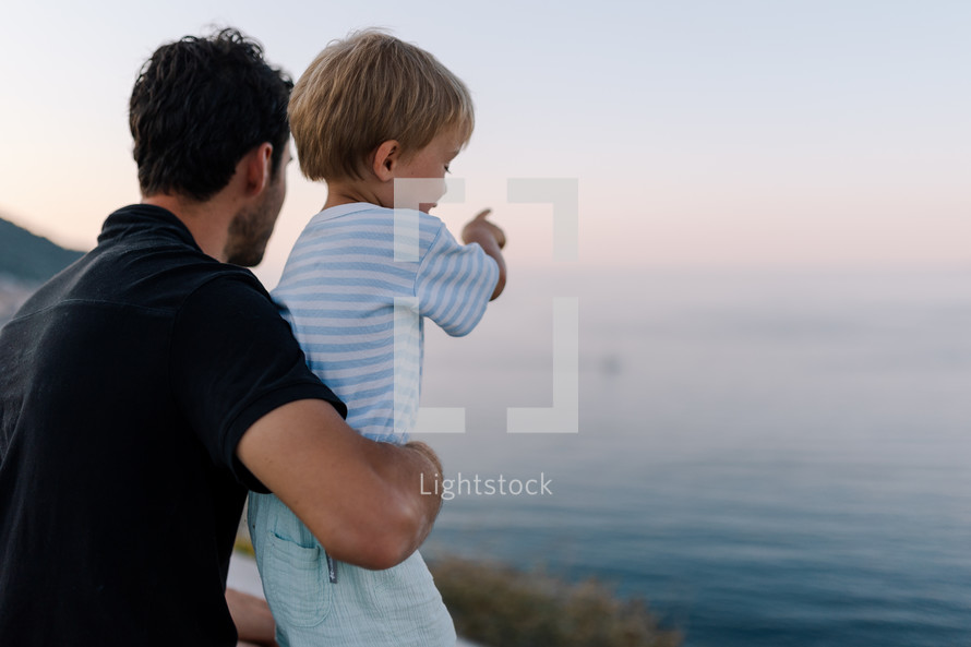 Son showing father a boat on the sea